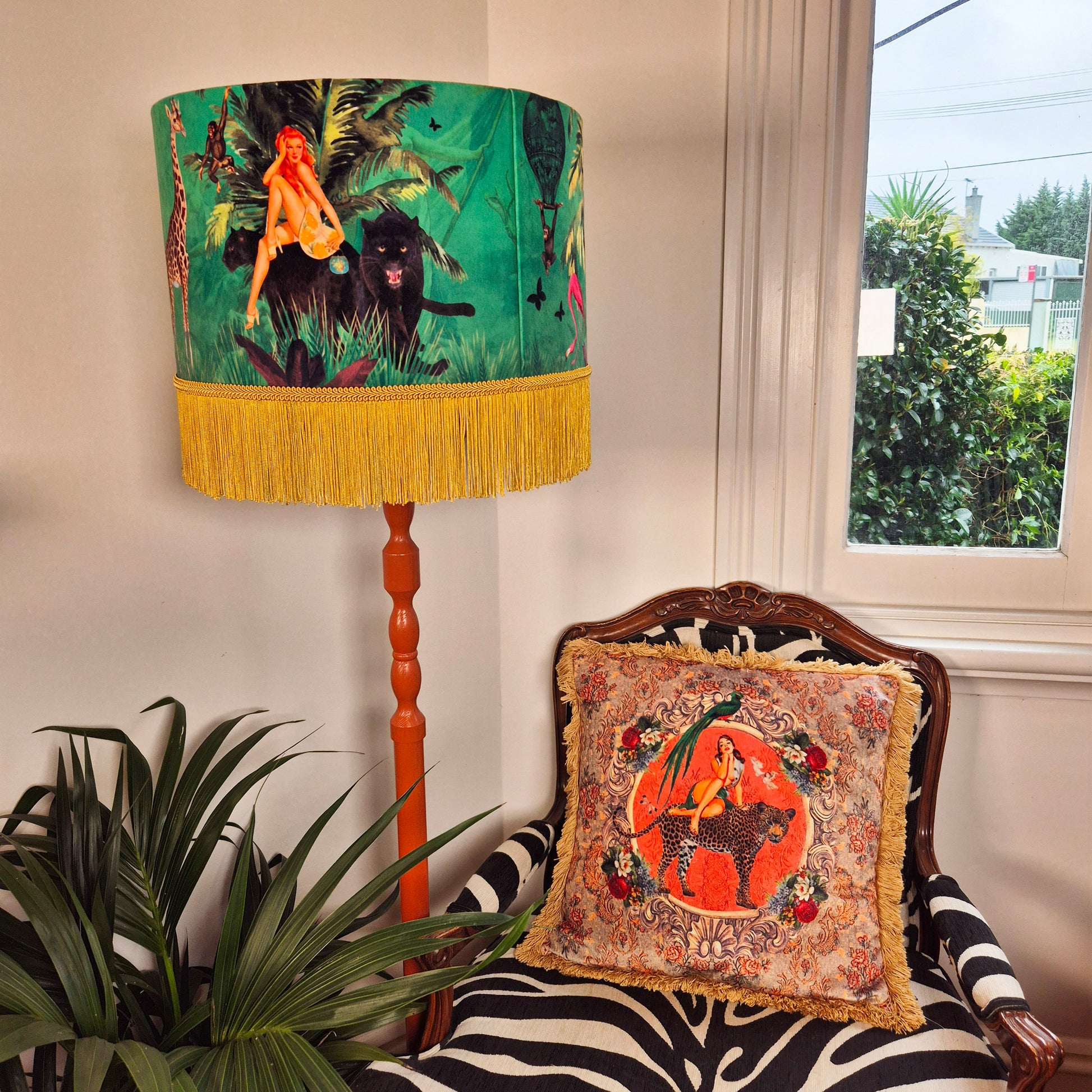 Alice vintage pin-up cushion with ornate floral design on a wooden chair next to a colorful jungle-themed lamp