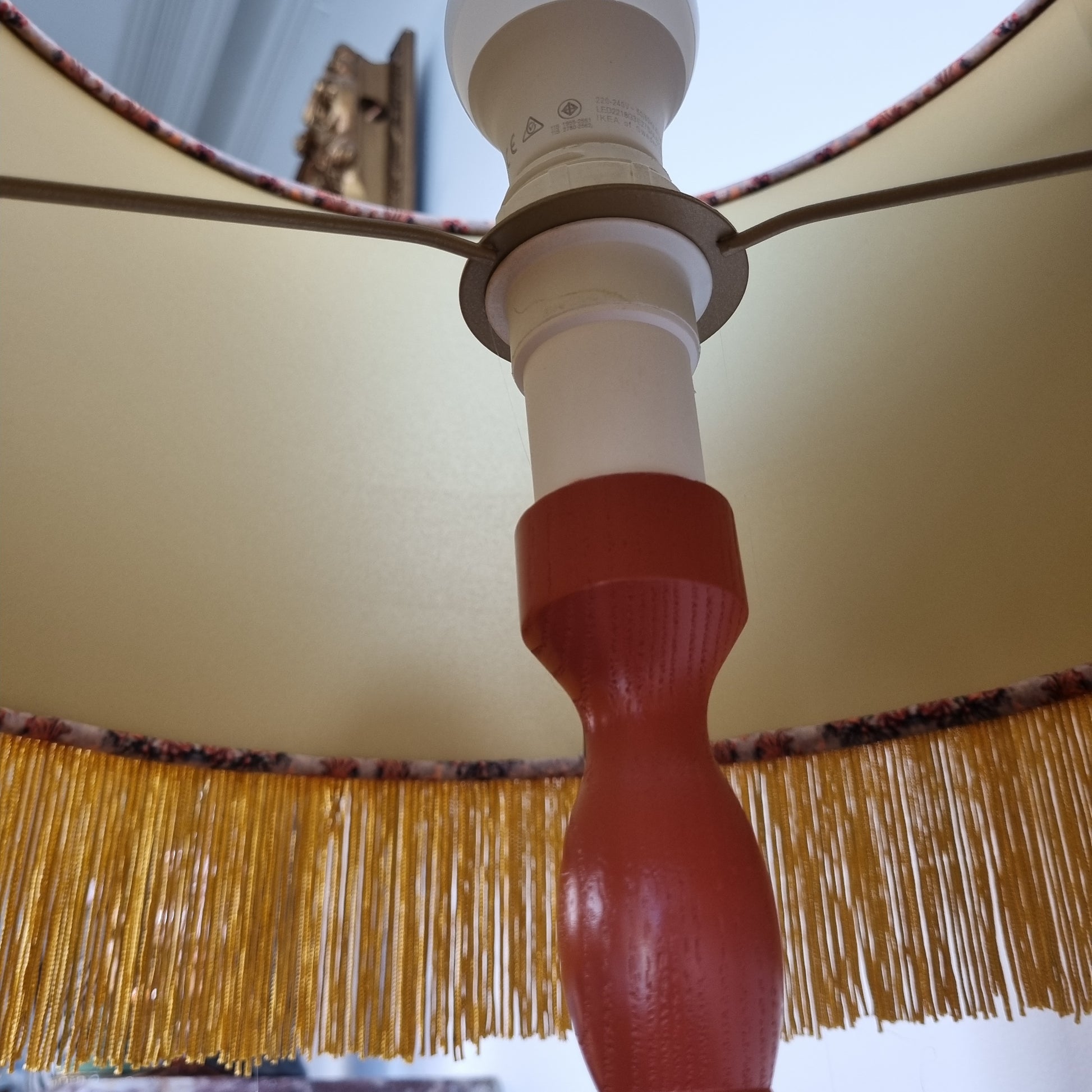Close-up view of Queen K Alice Vintage Tassel Drum Lamp shade with golden fringed trim on beige fabric