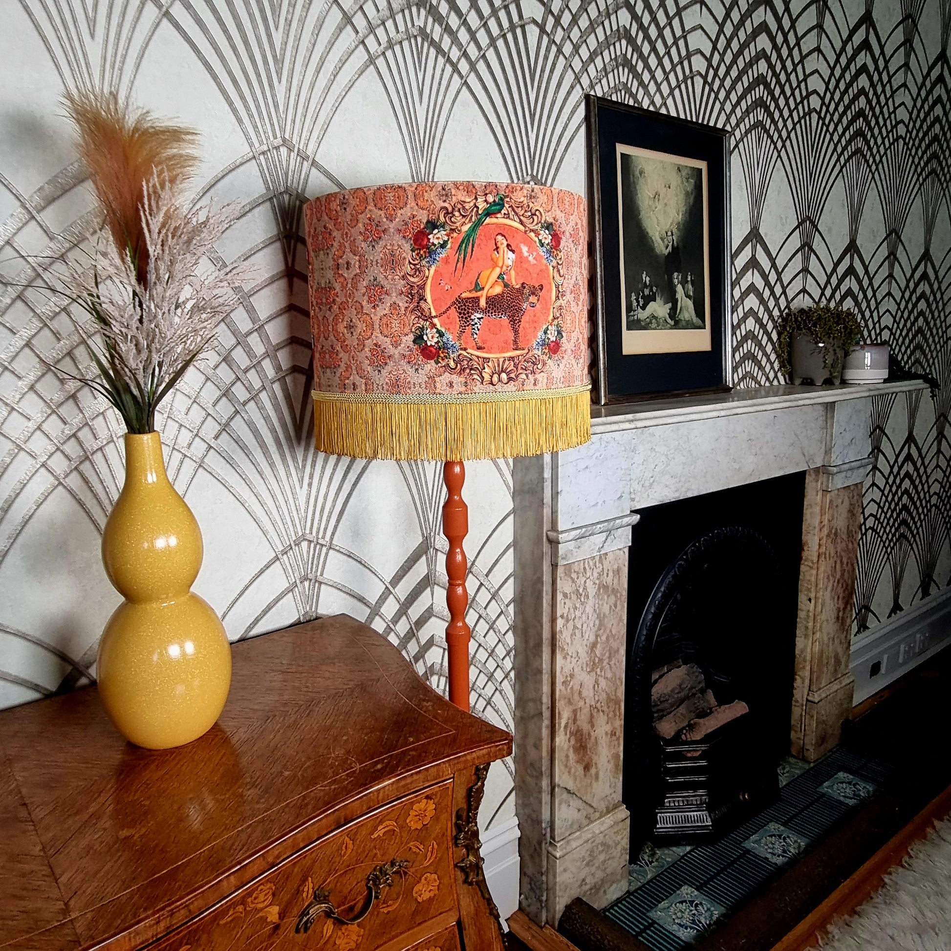 Alice Vintage Tassel Drum Lamp shade with yellow fringe on a wooden floor lamp by a fireplace