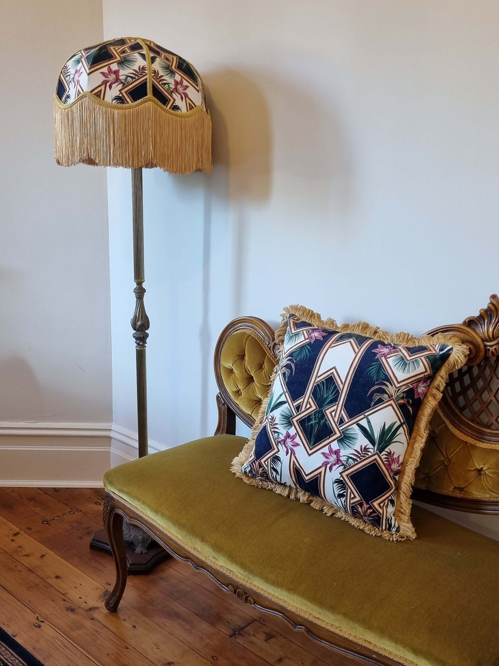 Queen K art deco cushion with geometric patterns and fringed edges on vintage green chair