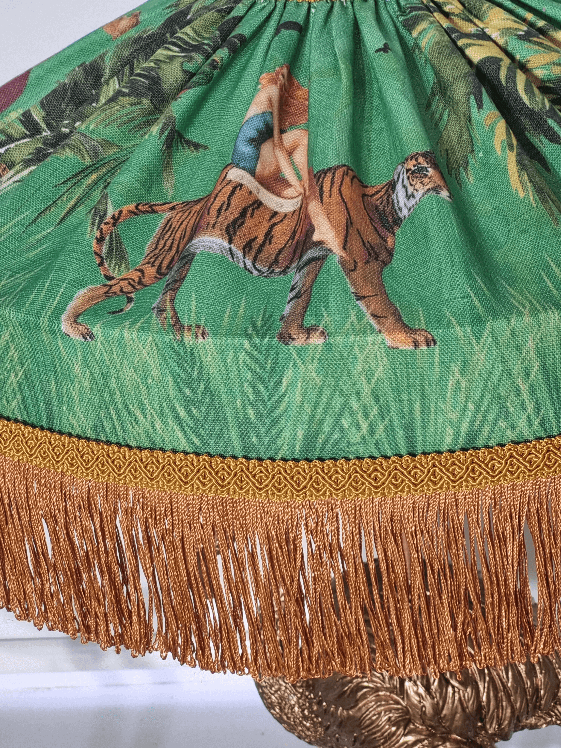 Queen K Jungle Walk Fringed Tiffany Lampshade featuring a woman riding a tiger with brown fringe trim