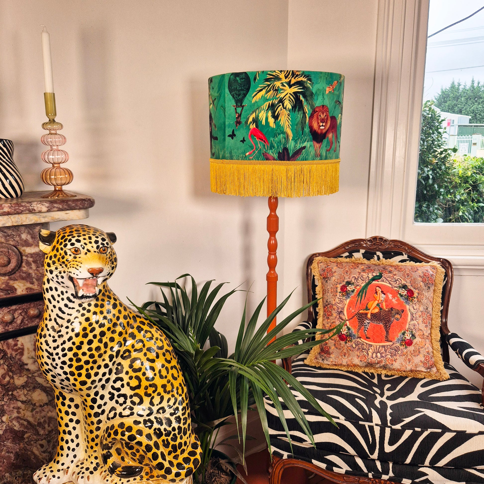 Jungle Walk Green Tassel Fringed Drum Lampshade by Queen K featuring jungle animal print with yellow tassels on wooden floor lamp