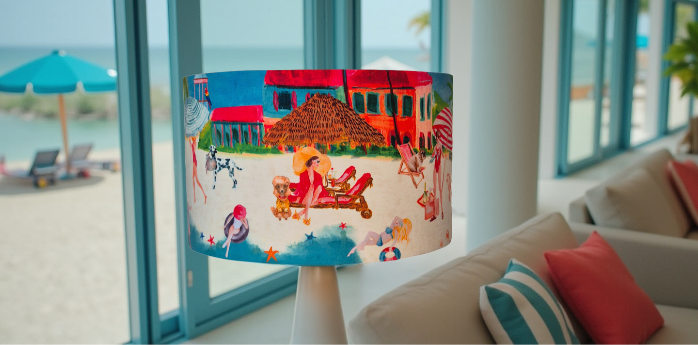 Queen K Riviera Drum Lampshade with colorful beach scene and fringed design on table lamp