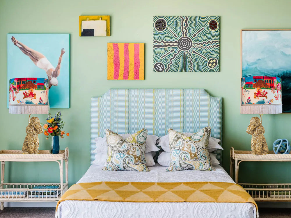 Queen K Riviera Fringed Drum Lampshade with colorful art and fringe on bedside lamps in a stylish bedroom