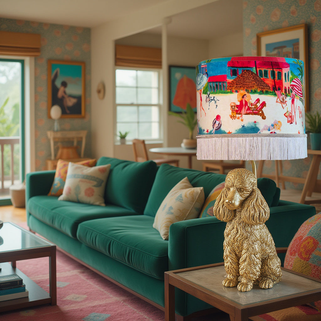 Riviera Fringed Drum Lampshade with colorful beach scene on a gold dog base lamp in cozy living room