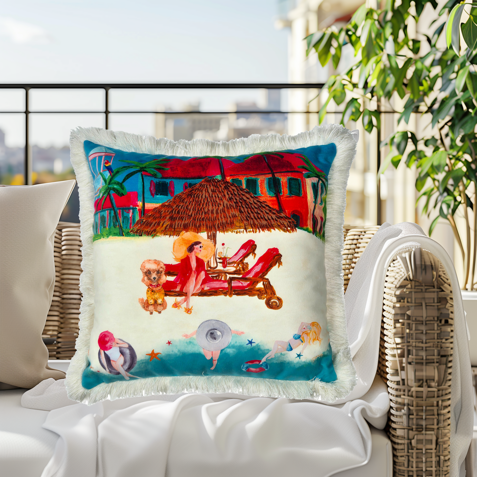 Queen K Riviera Fringed Velvet Cushion with colorful beach scene and white fringe on outdoor wicker chair