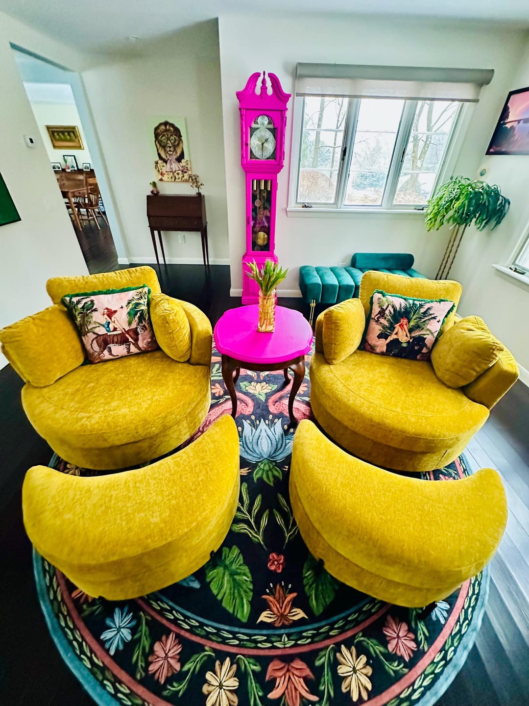 Yellow armchairs featuring handmade jungle print cushion in a bright living room with floral rug and pink table