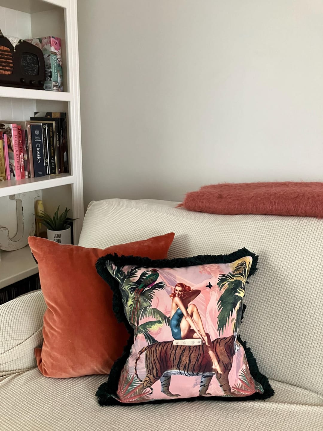 Queen K handmade jungle print cushion with tropical design and black fringe on beige sofa